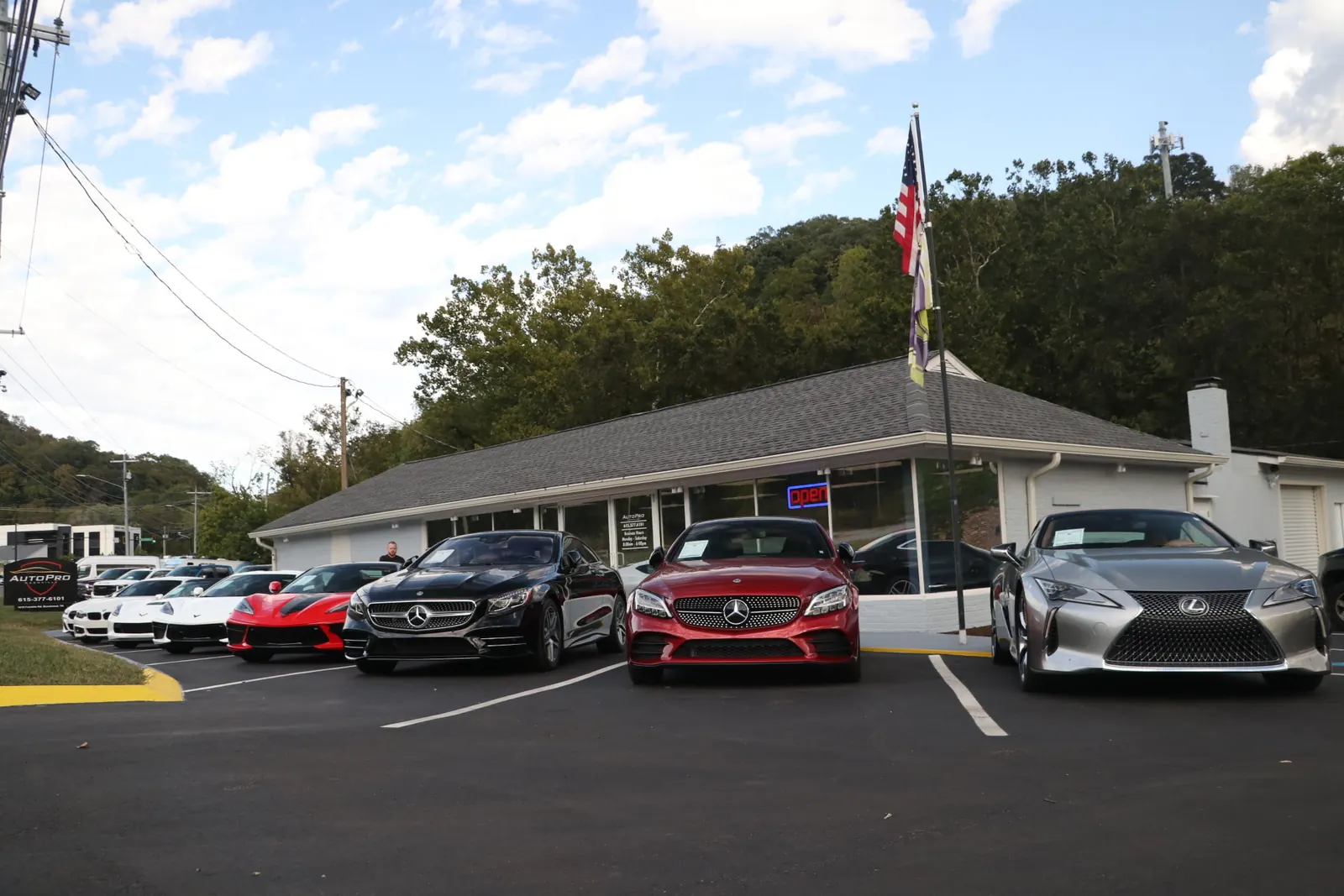The AutoPro of Nashville dealership in Brentwood, a one story building with an open sign and a flag, coupes parked along the front row