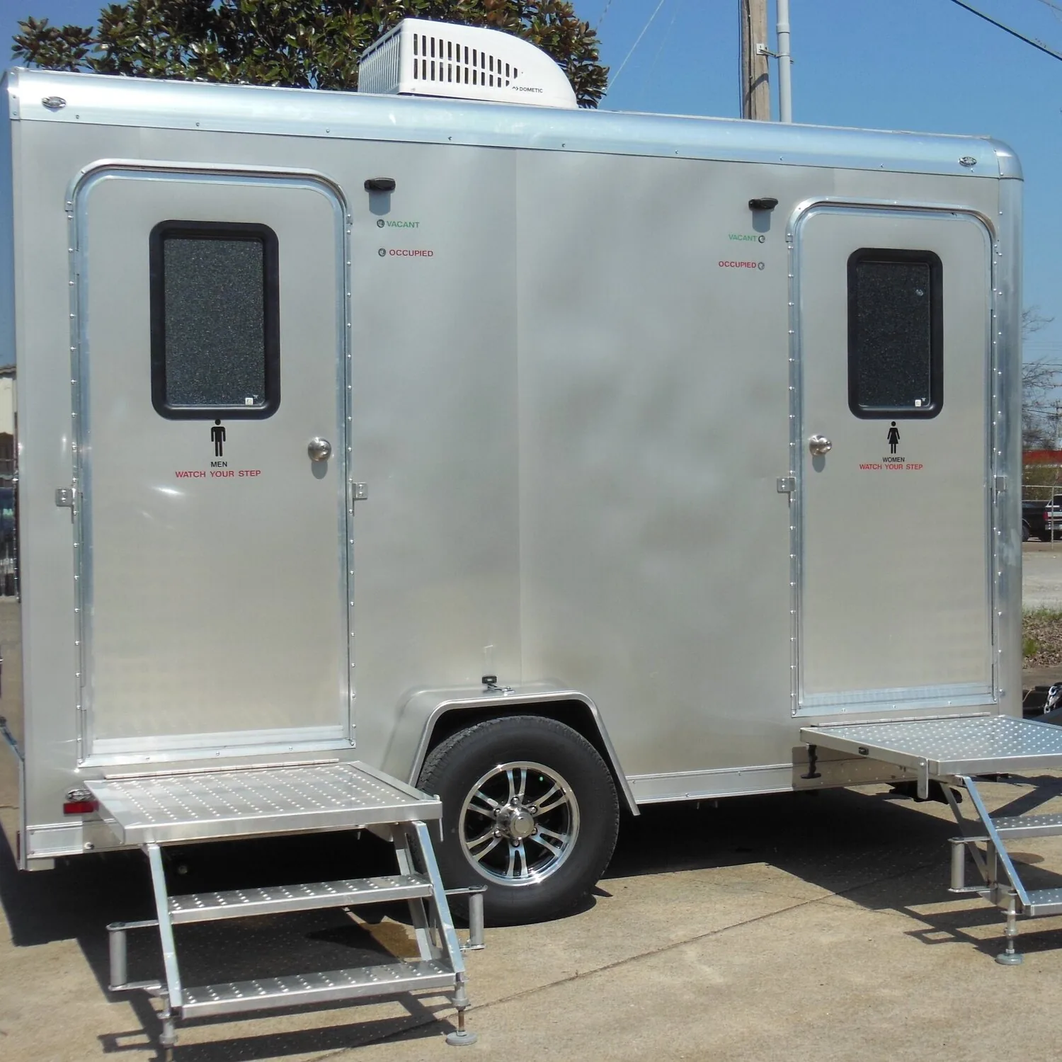 A silver two-stall restroom trailer with folding steps up to each door