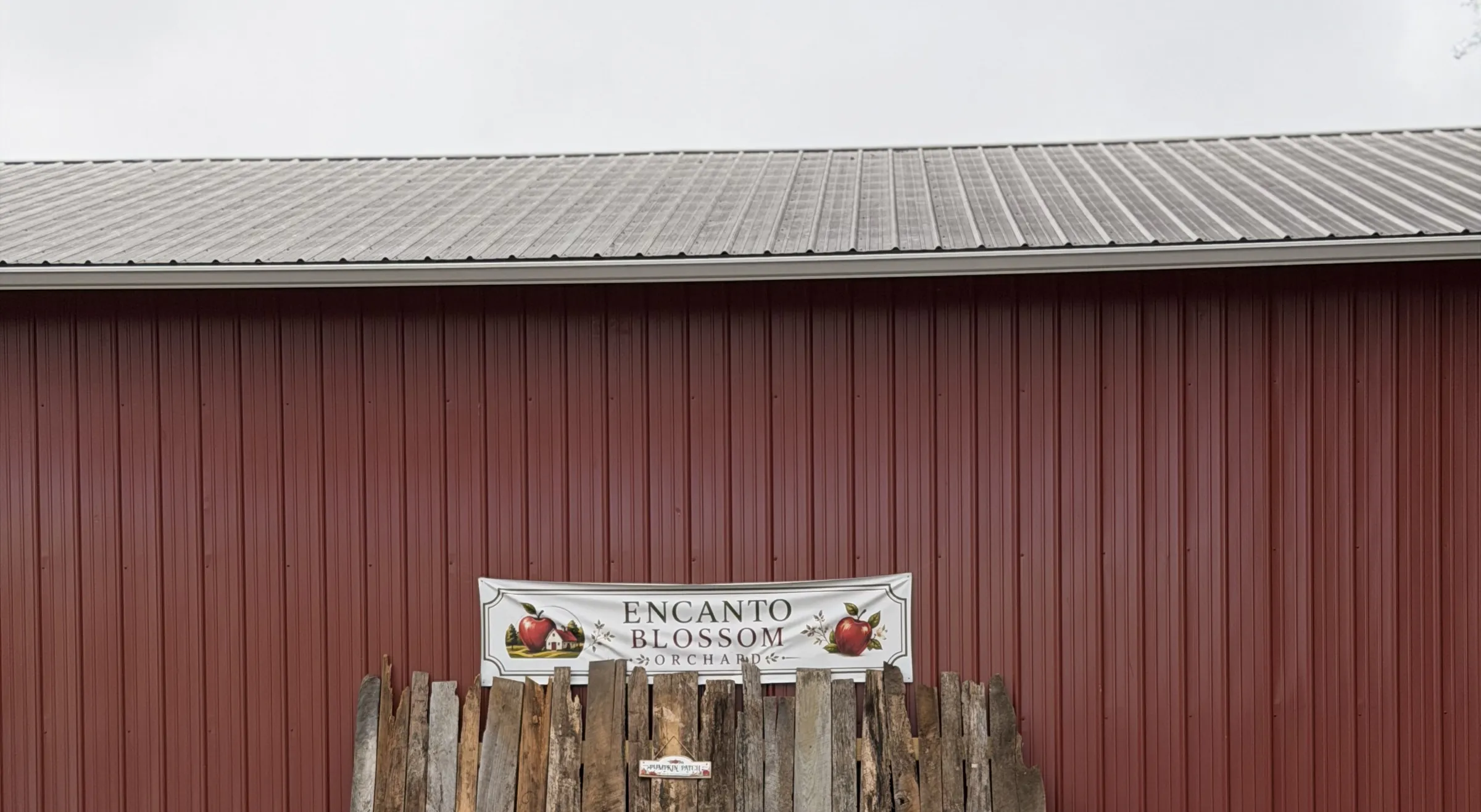 The Encanto banner on the red barn wall, on a weathered wood backdrop