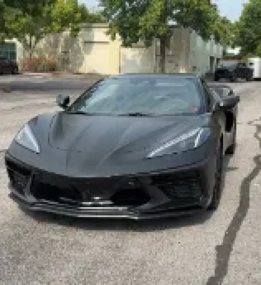A Corvette C8 in satin black parked outside the studio