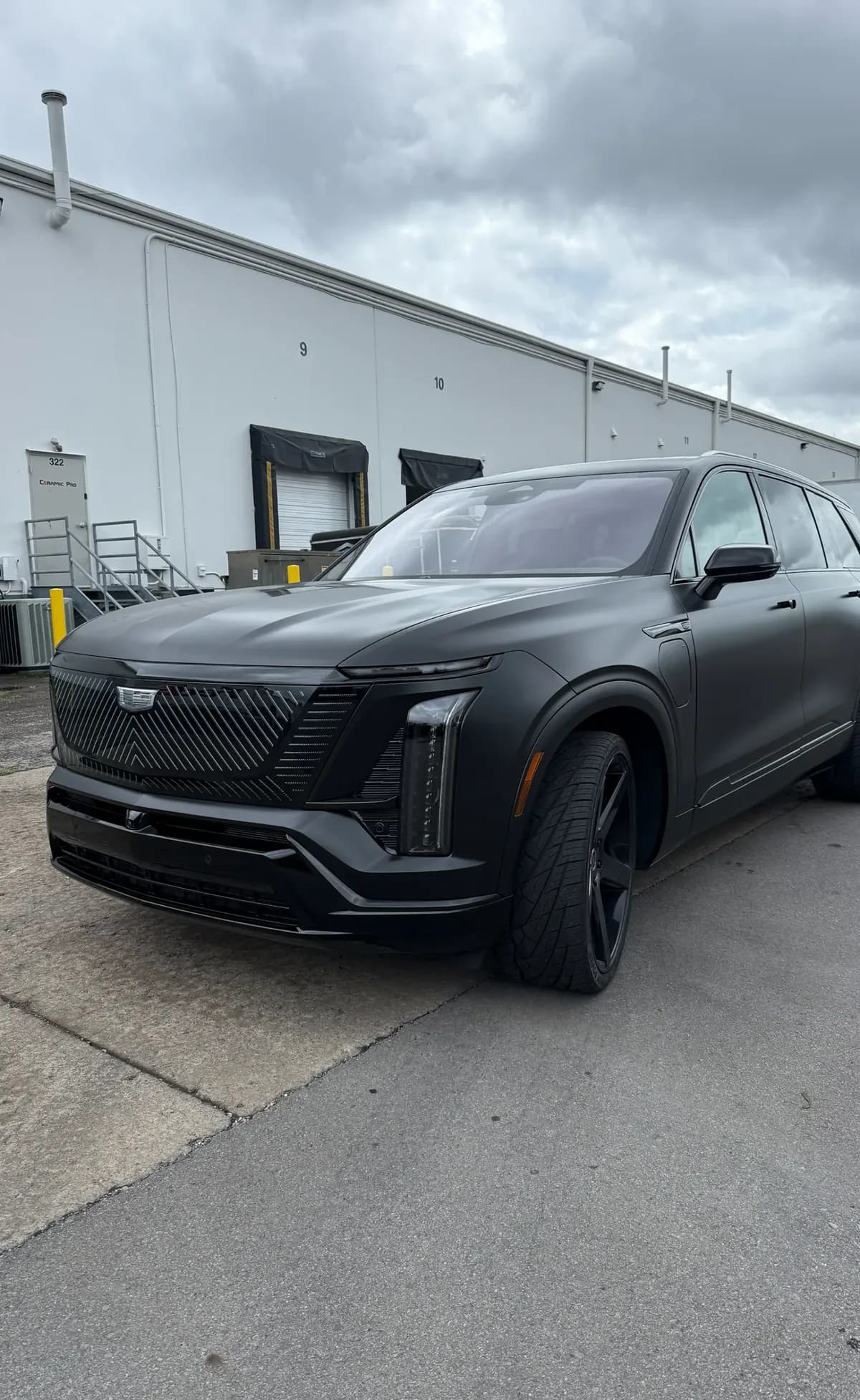 A Cadillac SUV in satin black parked by a loading dock