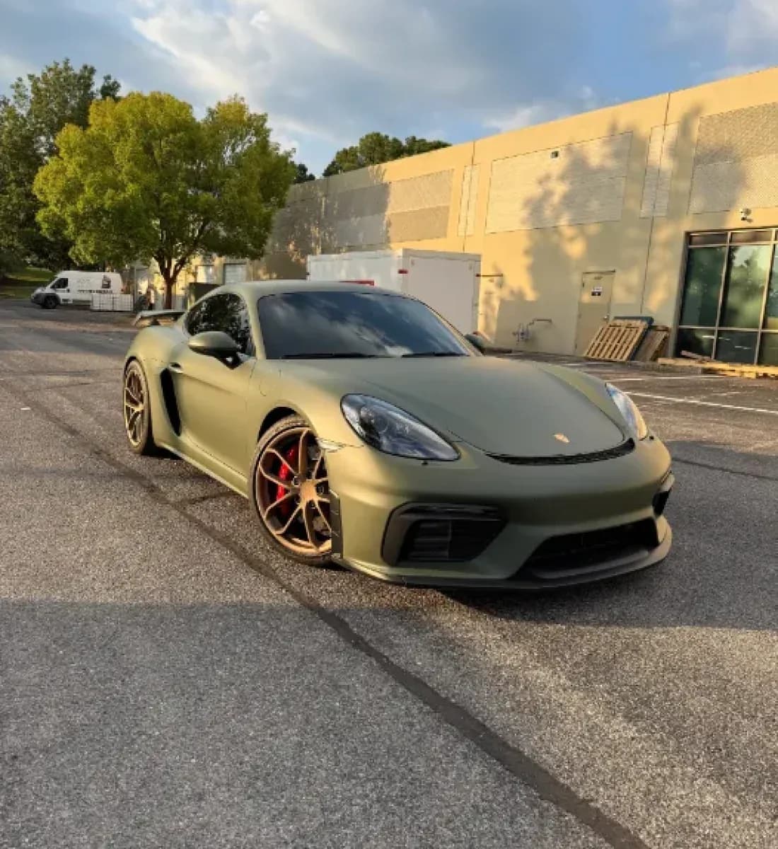 A Porsche Cayman GT4 in matte olive green parked outside the studio