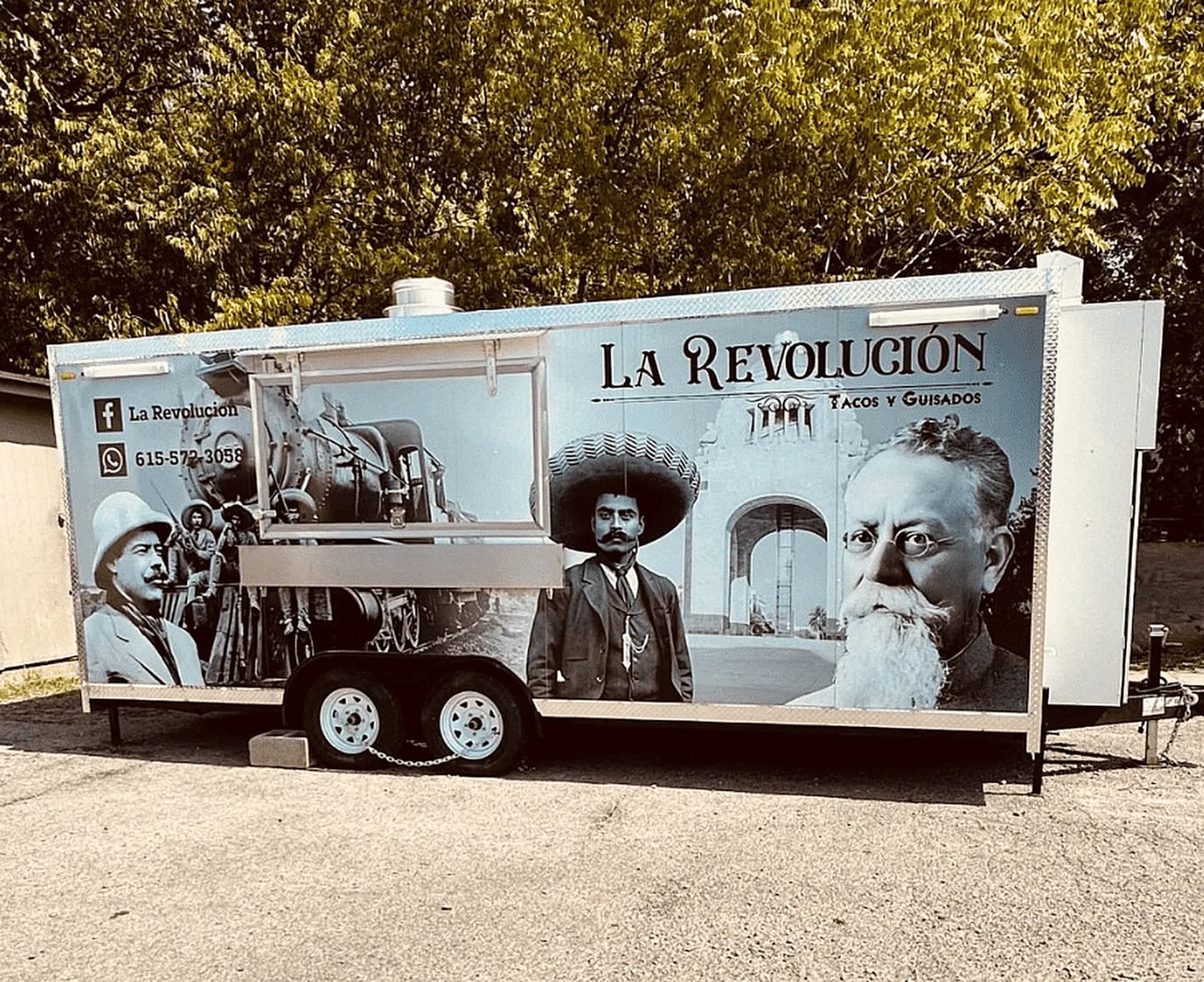 The La Revolución trailer parked under trees, its wrap printed with black and white portraits from the Mexican Revolution, the name La Revolución and Tacos y Guisados across the side, and a Facebook and WhatsApp number on the left