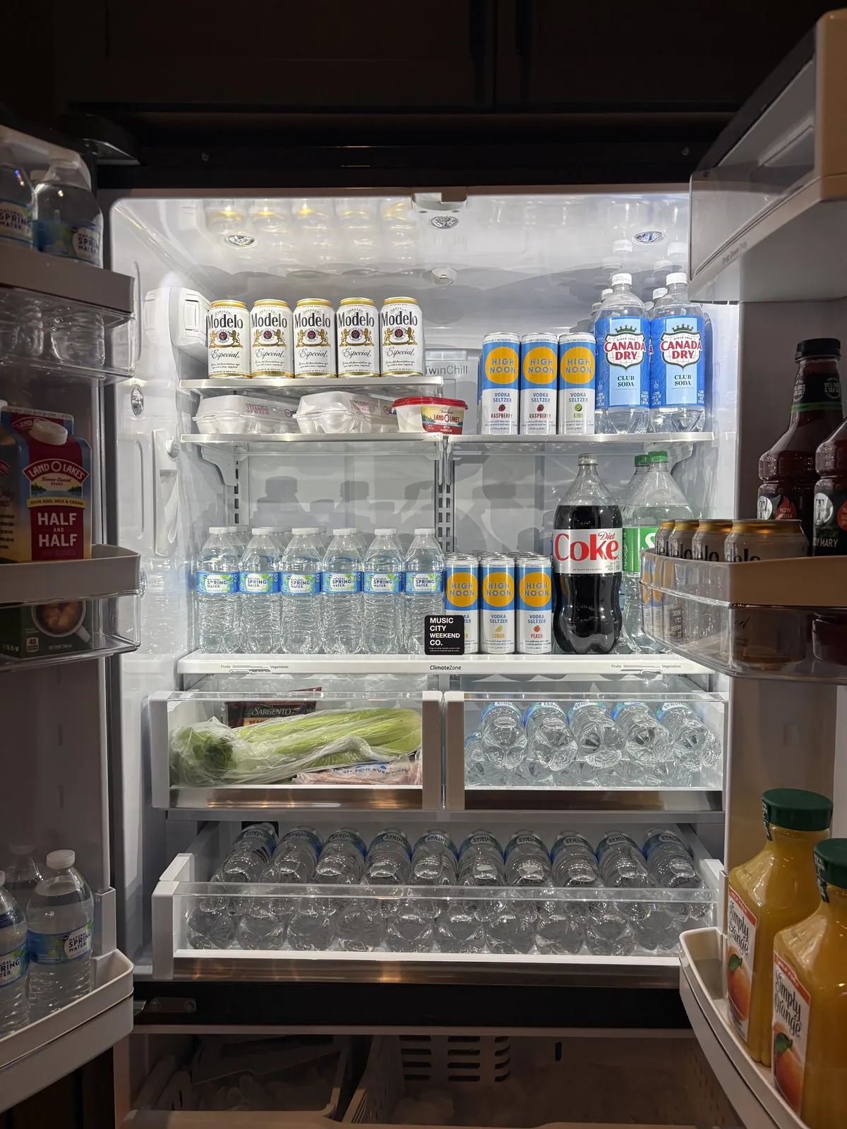 An open French door refrigerator stocked with drinks, bottled water and produce