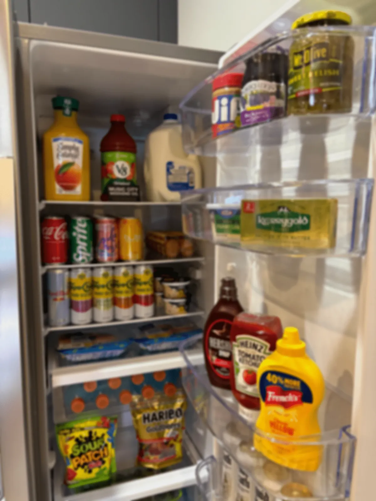 Refrigerator door shelves stocked with juice, milk, sodas, condiments and butter