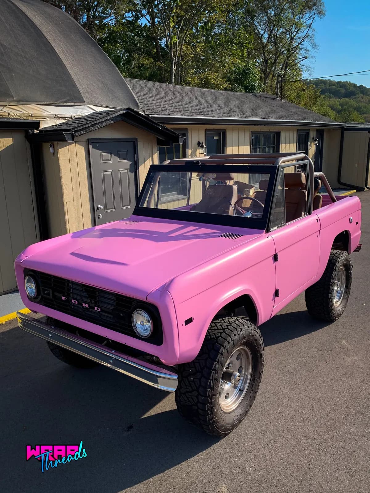 A pink vintage Ford Bronco with the top off