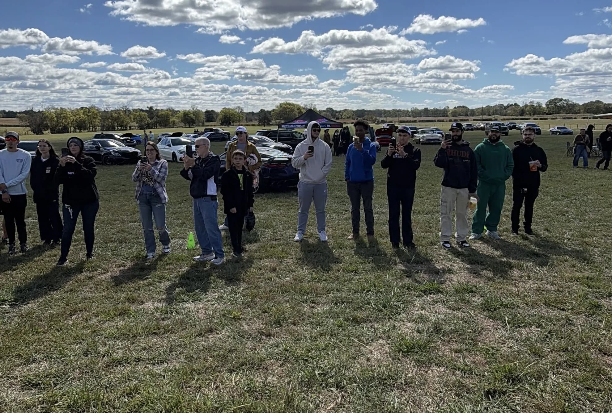 Guests standing together on the show field at Rancho Jaramillo on October 17, show cars parked behind them