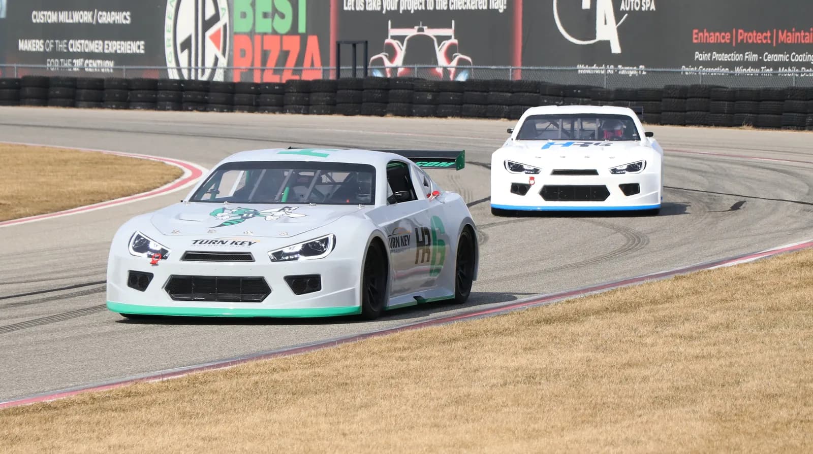 Two white Howe Racing HR6 race cars cornering on a track